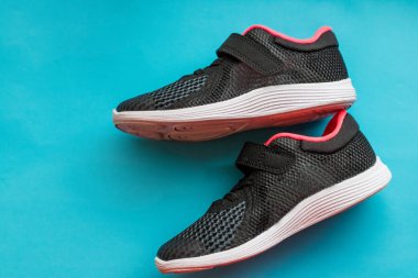 Mavi arka plan üzerinde spor ayakkabı. Çocuk izole siyah spor ayakkabı pembe. Yeni spor, koşu ayakkabıları izole dantel ile çifti