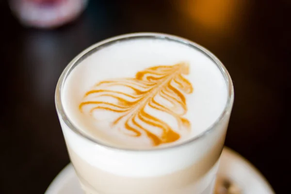 Fancy latte kaffe i glasburk. Glas kopp hett kaffe latte isolerade på dac bakgrund. Genomskinlig kopp kaffe mjölk och choklad och med silversked på tallrik. Drick kaffe latte i en tall — Stockfoto