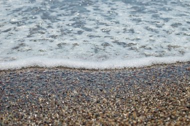 Deniz gelgit üzerinde çakıl plaj, güneş ışığı, doğa güzelliği, küçük taşlar ile su dalgası içinde güneş Light.pebble taşları deniz plaj, inişli çıkışlı dalgalar üzerinde. Yaz tatil kavramı