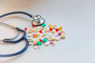 Stetoskop ile renkli antibiyotik kapsül hap ilaç tepsi ile beyaz tabloda yığını. Antimikrobiyal ilaç direnci ve aşırı. Doktor tıbbi donatımı. Küresel sağlık. Pharmaceuticals.he