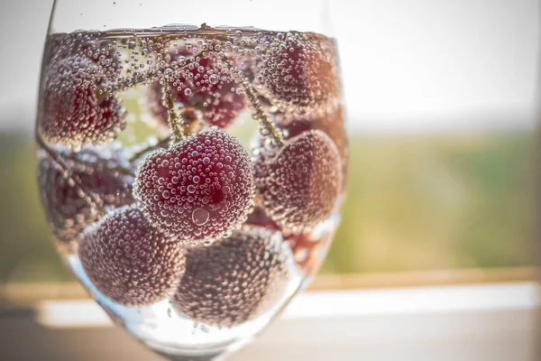 Cereja em água com gás com bolhas. Bebida refrescante fria do verão. Desintoxicação de água, Copo de água gelada de limonada com saborosas bagas cruas, cheriies vermelhos. Espaço de cópia — Fotografia de Stock