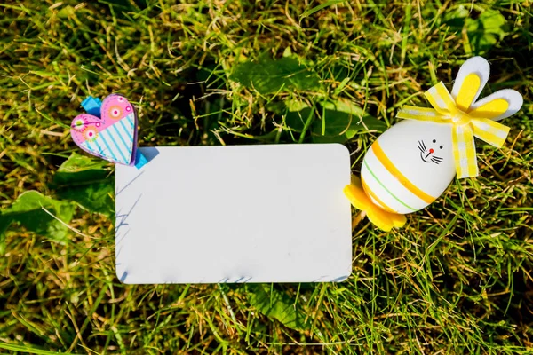 Blank greeting card with small easter eggs in the grass.Easter eggs on meadow. Spring holidays concept .Easter composition with easter eggs .Mockup white greeting card — Stock Photo, Image