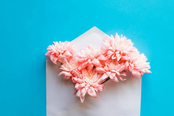 Fleurs fraîches magnifiques bouquet dans l'enveloppe sur fond bleu pastel, vue de dessus, espace de copie, lay.card plat pour la Saint Valentin ou la fête des mères. Mariage, anniversaire, invitation romantique . — Photo
