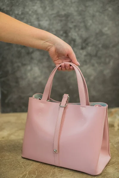 Woman hand hold stylish fashion pink leather bag handbag isolated on gray background.fashionable woman . Fashion elements.Trendy fashion Handbag Clutch clothes. Glamor fashion