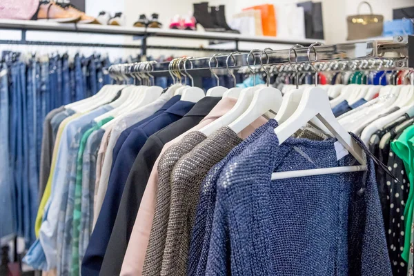 Interior of shopping. Clothing sales point women.outfits in a womens clothing store in a shopping center.Many wooden hangers with different female clothes in boutique on metal stand. Closeup, side — Stock Photo, Image