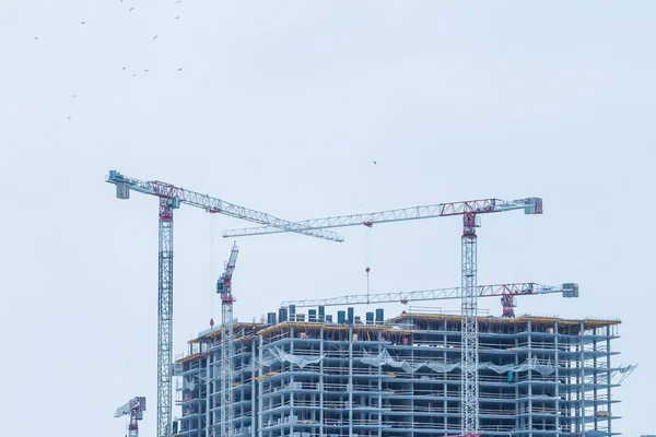 Construction site background. Hoisting cranes and new multi-storey buildings. Industrial background.modern urban building under construction with a crane. Industrial modern residential quarter of the