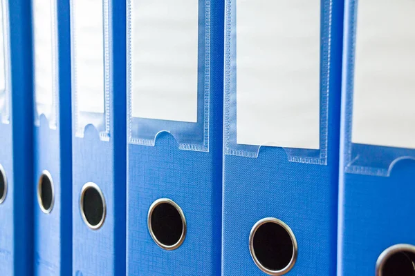 Dossiers de bureau isolés. Rangée de dossiers de bureau bleus avec des étiquettes vierges sur le bureau.Dossiers et documents organisés et rangés dans des étagères. Organisation des documents . — Photo