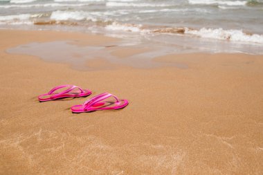 Açık kumlu plaj pembe parmak arası terlik. Hafif kum dokusu. Plaj tatili kavramı. Yaz konsepti. Düz yatıyordu, yan görünüm, kopya alanı. Tropikal tatil konsepti