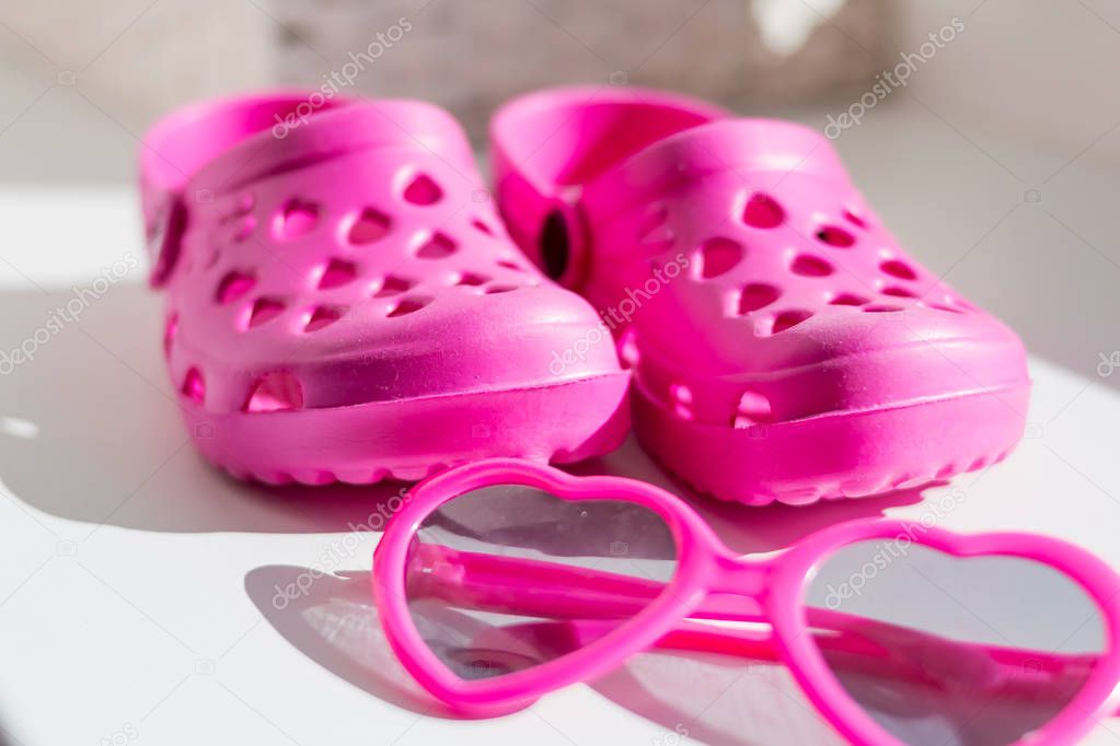 Pink rubber slippers, isolated on white background. Childrens rubber sandals isolated.Comfortable shoes for beach, garden.Summer fashion and sunglasses