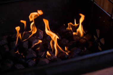 Ateşte sıcak kömürler.barbeküde yanan kömürler, ızgarada ateş.ızgaraya hazırlanan kömür, barbekü ızgarası. Alevler ve kömürler geceleri yanan bir ateş . Sıcak kömürlerin arka planı.