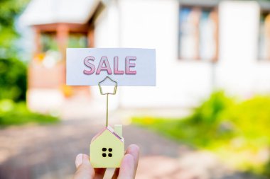 Ev ve satış tahtası küçük bir model. bir konut ve emekli kavramları için para tasarrufu. Gayrimenkul, Tasarruf ve ev ipotek ve kredi Sigorta ve Bankacılık kavramı satın alma. Kavramsal görüntü