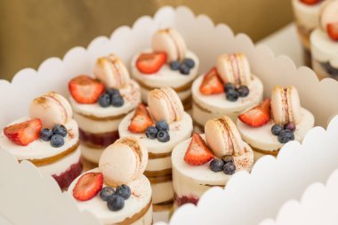 Çeşitli mini kekler. Tatlılar tatil için taze çilek ile dekore. lezzetli kek. çeşitli çilek ve vanilya krem, çilek ve renkli Makaron ile küçük kekler. Macaroon tatlı Meringue tabanlı