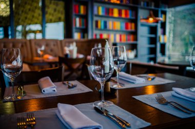 Gözlük, çiçekler, çatal, bıçak rahat iç mekan, Retro Film filtre efekti ile restoranda akşam yemeği için servis. Seçmeli odak. Restoran İç, modern ayar, şarap gözlükleri, tekstil peçeteler üzerinde. Kavram