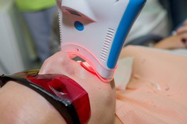 kız ultraviyole lamba yardımıyla diş beyazlatma prosedürü uğrar.klinikte diş hekimi kadın hasta. Ultraviyole ışık Uv lamba ile diş beyazlatma prosedürü.