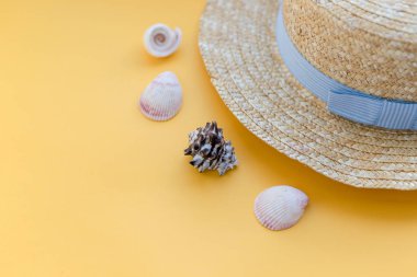 Sarı arka plan üzerinde deniz kabukları ile Yaz hasır şapka plaj. Yaz aksesuarları. Düz yatıyordu plaj aksesuarları. Yaz saatleri ve seyahat için konsept. Womans plaj aksesuarları düz yatıyordu.