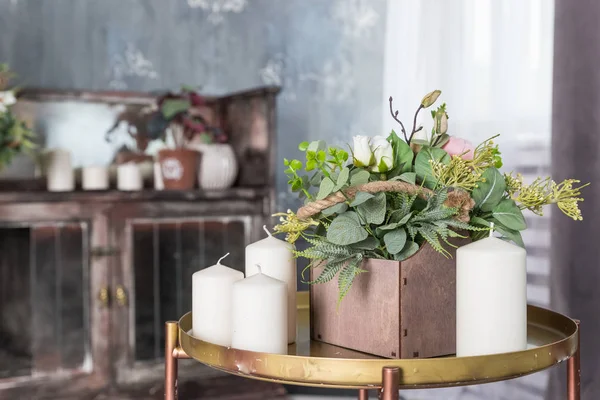 Biologische geurende soja kaars op kleine tafel. Loft interieur, minimalisme concept. Home interieur decoratief item op tafel met houten kist met bloemen, witte kaarsen. — Stockfoto