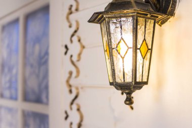 beyaz duvara karşı demir fener yanan. Akşamları açık havada bir duvarda Fenerler. Streetlight.Klasik Fener.