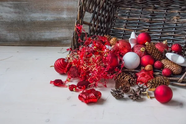 Christmas basket with decor, gifts with red satin ribbon, candy canes, pine cones, red and white garlands on white wooden background. Happy new year, holidays concept — Stock Photo, Image