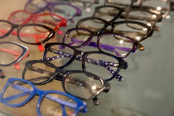 El expositor de los cristales que consisten de las baldas de los cristales a la moda mostrados en la pared en la tienda óptica. Gafas Graduadas Elegantes Coloridas en una tienda.Enfoque selectivo —  Fotos de Stock