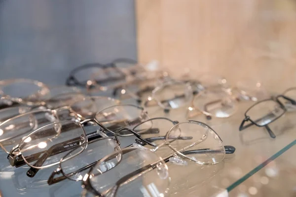 Óptica, cuidado de la salud y concepto de visión - primer plano de las gafas en optician.exhibitor de gafas que consisten en estantes de gafas de moda que se muestran en una pared en la tienda óptica.Enfoque selectivo —  Fotos de Stock
