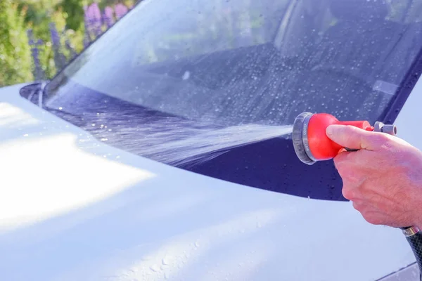 Carros a aquecer. Trabalhador de limpeza carro branco ao ar livre.Limpeza de carro usando água de alta pressão. Homem lavando seu carro sob água de alta pressão em serviço.Limpeza do carro. Lavagem de carro com sabão . — Fotografia de Stock