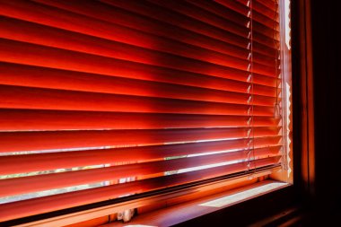 Kapalı turuncu plastik güneş ışığı ile sabah güneş ışığı ile. panjurlu pencere. Pencere yatay panjur ile oturma odası iç tasarımı. Güneşli bir günde kapalı jalousie. Gölge ve ışık