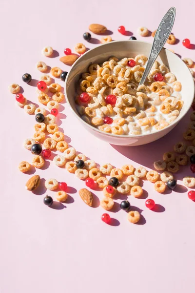 Wholegrain flakes with berries and milk on pink. Healthy tasty breakfast cornflakes with blueberries, raspberries and red currant.Multigrain wholewheat healthy cereals with fresh berry. — Stock Photo, Image