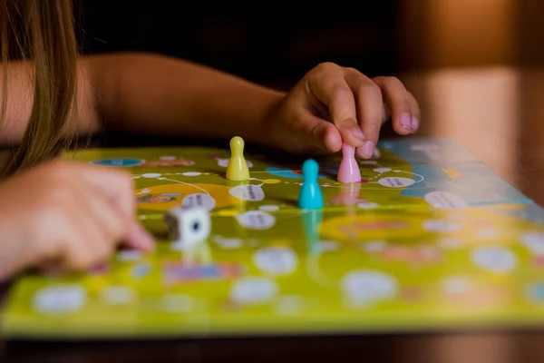 Multi-colored game chips with dice on the playing board. Board game.children sit in kindergarten at the table engaged, learn in the nursery,Playing table game. — Stock Photo, Image
