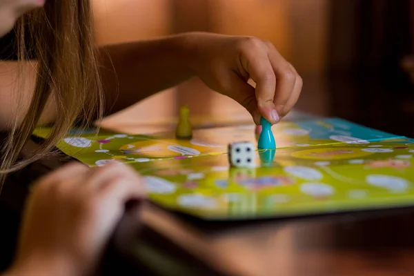 Multi-colored game chips with dice on the playing board. Board game.children sit in kindergarten at the table engaged, learn in the nursery,Playing table game. — Stock Photo, Image