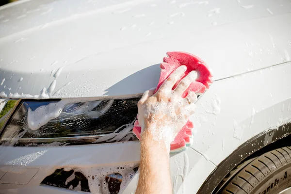 Manliga handen håller svamp för tvättning vit bil. Dirty Auto. Man Worker tvätt vindruta med svamp på en biltvätt. Manuell biltvätt i biltvätt Shop service — Stockfoto