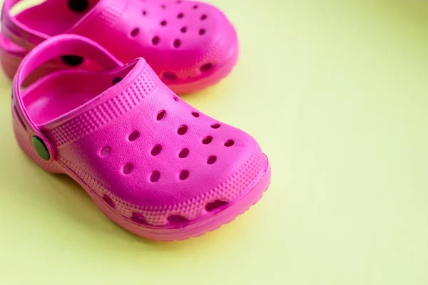 San Diego, USA, maj 10, 2019. Summer Pink flip flops isolerade på gul bakgrund. barn mjuka gummisandaler eller Crocs. sommarlov trendiga skor, sandaler. snygga barn sandaler. rosa skor — Stockfoto