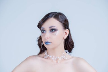 Eski moda saç kesimi olan çekici bir model, şık saç stili olan seksi bir model, uzun bacaklar, mükemmel bir ten, parlak bir kolye takıyor. Yaratıcı parlak dumanlı gözler ve mavi dudaklar. Boşluğu kopyala