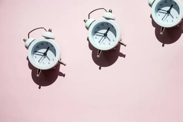 Layout criativo de relógios de alarme brancos no fundo rosa pastel. Conceito minimal.Acorde o conceito de alerta. De manhã. De volta ao conceito de escola. Design minimalista estilo. Design de embalagem. Criativa — Fotografia de Stock