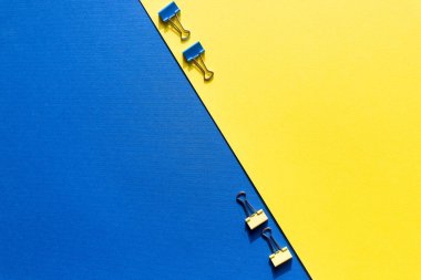 Fotokopi alanı olan renkli ataçlar. İş yaratıcılığı kavramları. Düz dizayn. Sarı mavi arkaplana renkli renkli ataçlar. minimalizm tarzı, üstten görüntü.