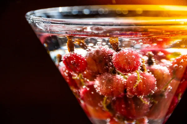 Copa de refrescante bebida fría de verano con bayas y cubitos de hielo en la mesa close up. Refrescante bebida de verano con grosella . — Foto de Stock