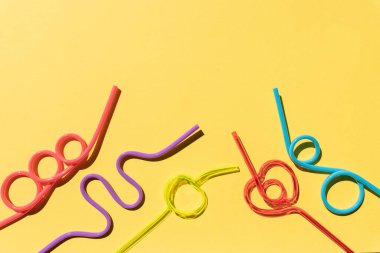 Sarı arka planda izole edilmiş spiral renkli kokteyl tüpleri. Parti pipetleri. Renkli kokteyl. Parti kavramı, kutlamalar. Boşluğu kopyala.