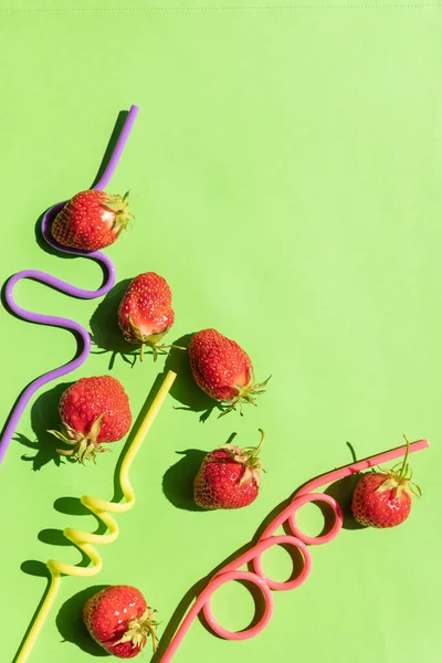 Creative layout strawberry lemonade ingredients.cocktail straws on green background. Funny drinking straws.Summer drinks. Minimal food concept. Party, holidays card. Copy space