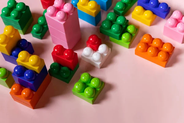 Close up de tijolos de plástico coloridos na mesa. diversão e construção de tijolos brilhantes construtor. Aprendizagem precoce. fundo rosa. Desenvolvendo brinquedos. Blocos de construção de plástico brilhante — Fotografia de Stock