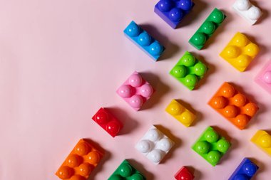 Oyuncaklar çerçeveyi bloklar, canlı plastik yapı tuğlaları, renkli oyun taşları grubu. Pembe arka planda renkli bebek oyuncakları. Geliştirme. Yaratıcı, mantıklı düşünme konsepti. Düz yatıyordu. Boşluğu kopyala.