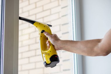 Pencereleri elektrikli süpürgeyle temizliyorum. Modern binanın cam temizleme işçisi. Erkekler portatif elektrikli süpürgeyle el ele tutuşuyorlar..