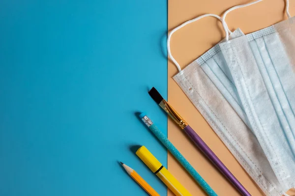 School stationery supplies, medical mask. After pandemic, new rules for school concept.Medical hygienic masks and education supplies, stationery equipment