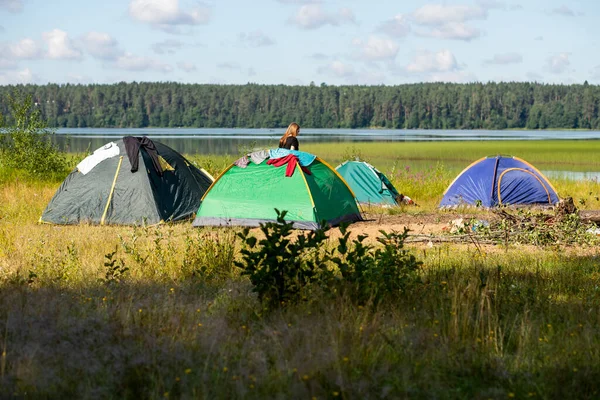 A tent set up in a rugged campsite, at the edge of a lake.Camping colorful tent on the shore of the lake, tourist tent on the shore of the pond.rest at nature. active tourism concept