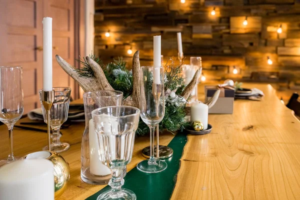Un tavolo da pranzo natalizio decorato con bicchieri di vino e luci di Natale.Apparecchiatura della tavola festiva tra decorazioni invernali e candele bianche. cena. nuovo ornamento candela anno su tavolo di legno — Foto Stock