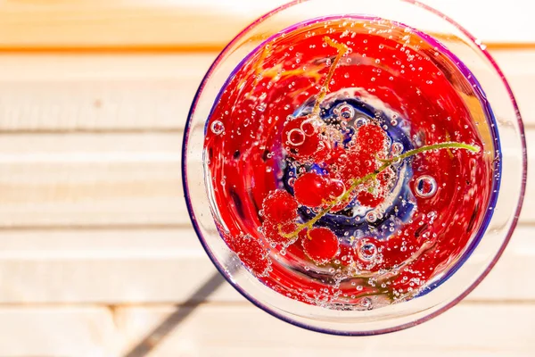 Refrescante chá de gelo de verão ou limonada com berries.fresh fresco espremido suco vermelho com groselha vermelha em uma mesa de madeira branca.Glass de bebida fria de verão com bagas vermelhas e cubos de gelo — Fotografia de Stock