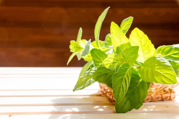Mint segar dalam mangkuk di atas meja kayu. Fokus selektif. Mint. Sekumpulan daun mint organik hijau segar dengan latar belakang kayu. Peppermint dalam keranjang kecil di bawah sinar matahari. Salin ruang — Stok Foto