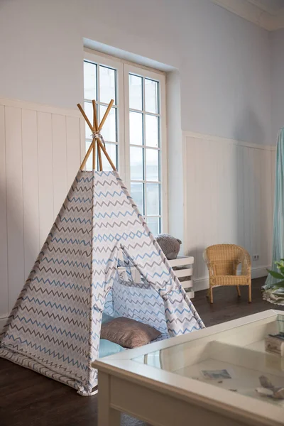 Odada oyuncakları olan çocuk kulübesi. Çocuk odasının içinde çocuklar için çadır kulübesi var. Boho tarzında oyunlar, çocuk odasının içi çok aydınlık. Wingwamwam tarzında.