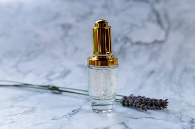 Doğal kozmetik cilt bakımı şişesi ve altın parıltı. Hyaluronik asit damlası, taze lavanta çiçekli altın şişe. Yaşlanma önleyici kollajen serumu. Güzel.