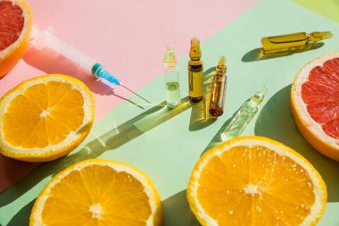 C vitamini organik kozmetik konseptli ampuller ve Serum. Limon, portakal, greyfurt ve ampul. Vitamin enjeksiyonu. Komineral takviye konsepti. Güzellik ürünleri.
