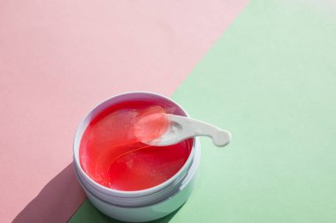 Pastel arka planda cilt bakımı için hidrojel kozmetik göz bandı. Yüz gerdirme, yaşlanma önleyici kırışıklık önleyici ürünler. Beyaz bir kapta göz altı yamaları, yaşlanma önleyici cilt bakımı. Kopya alanı.