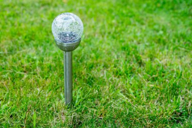 Bahçedeki güneş pili lambası ve elektrik enerjisinden tasarruf edip dünyamı kurtarın. Güneşli bir günde bahçedeki güneş lambasını şarj etmek yenilenebilir enerji kavramı. Dekoratif spot ışığı.